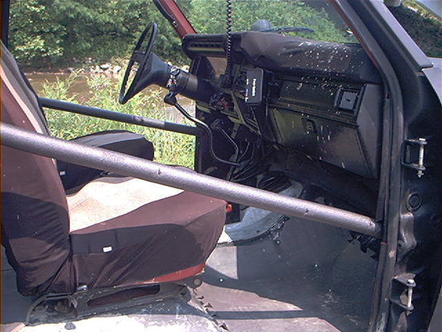 Interior of a modified off-road vehicle, showing seats, roll cage, and dashboard
