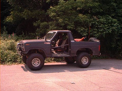 1986 Ford Bronco - This lifted SUV, likely from the early 1980s, is shown with its doors removed and a roll cage installed.
