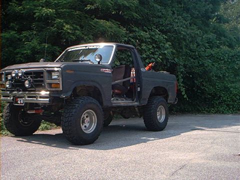 1986 Ford Bronco - This modified Ford Bronco features large off-road tires and a roll cage, suggesting it's built for terrain.