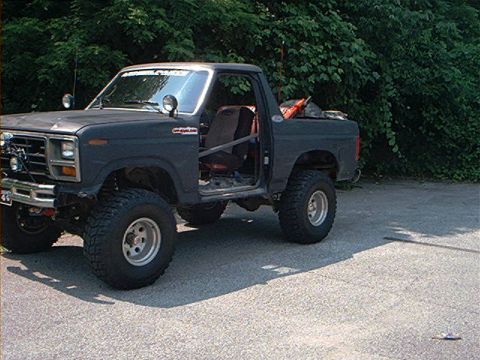 1986 Ford Bronco - This modified SUV features off-road tires and a roll cage, with its doors removed.