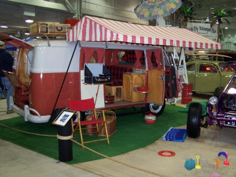 1995 Ford Probe - A vintage Volkswagen Type 2 camper van is displayed with its interior open, alongside other vehicles at a show.
