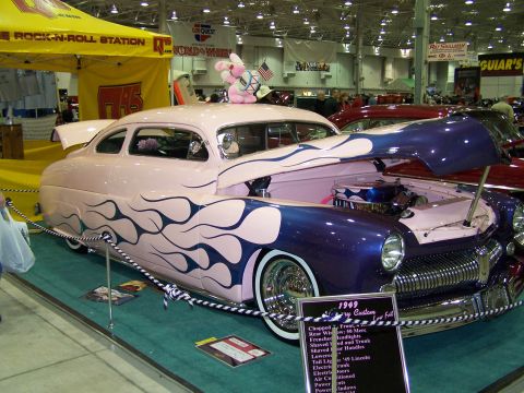 1995 Ford Probe - A 1949 Mercury Custom hot rod, painted pink with blue flames and a pink bunny on the roof, is displayed with its hood open.