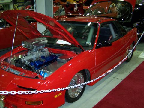 1995 Ford Probe - A red 1995 Ford Probe is displayed with its hood open, revealing a prominent supercharged engine.