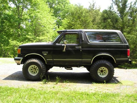 1988 Ford Bronco - This black 1988 Ford Bronco is shown in profile against a backdrop of trees.