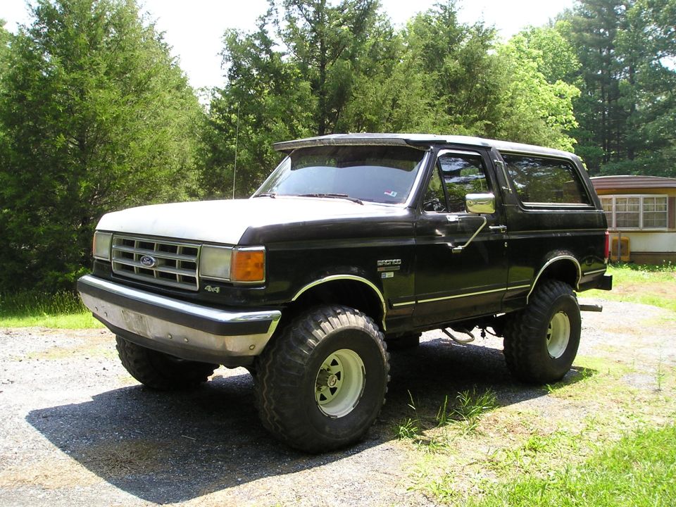 Lifted black Ford Bronco with white top, parked outside