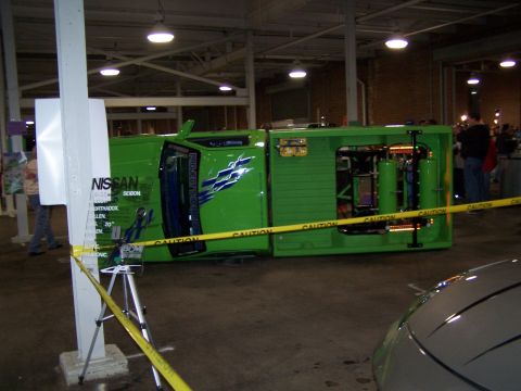 1995 Ford Probe - A modified green Nissan SEIBON vehicle is displayed on its side, revealing its interior mechanics and custom paint job.