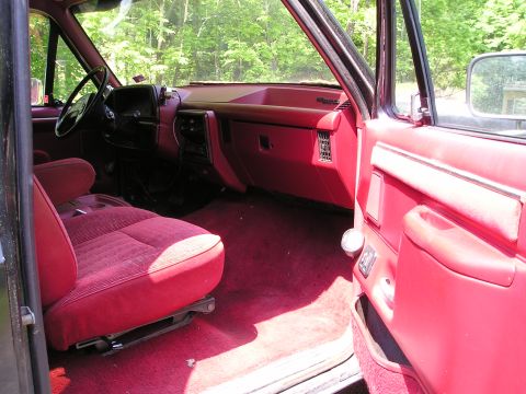 1988 Ford Bronco - The red interior of a 1988 Ford Bronco, plush carpeting and cloth seats.