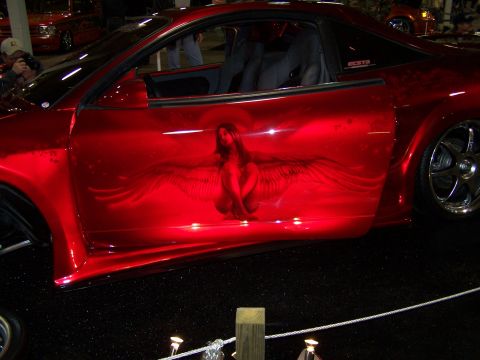 1995 Ford Probe - Custom red car with airbrushed art on the side door. Year is not discernible from the image.