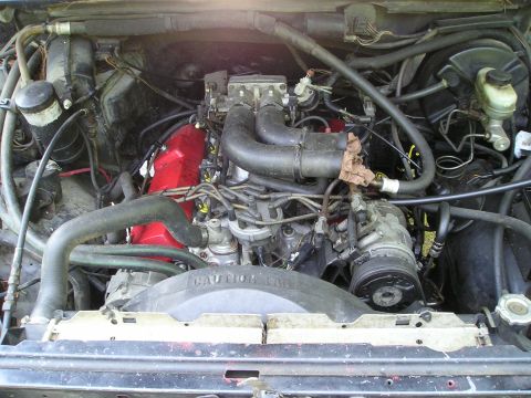 1988 Ford Bronco - Engine bay view showing V8 engine components and fan shroud.