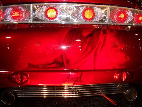 1995 Ford Probe - The rear of a red car displays an airbrushed angel graphic and the word 'Angel' on the bumper.