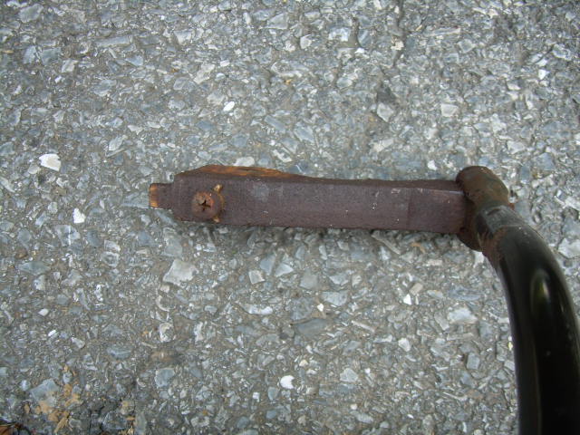 Rusty shift arm with corroded screw and black lever tube on concrete