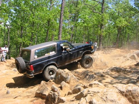 1988 Ford Bronco - Ford Bronco tackling a challenging off-road course with steep inclines and large rocks.