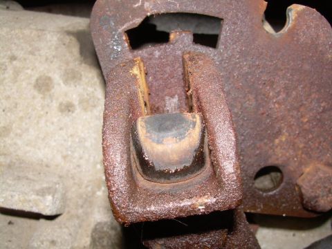 1988 Ford Bronco - Close-up of a heavily rusted metal bracket with a worn rubber bushing, likely a vehicle part.