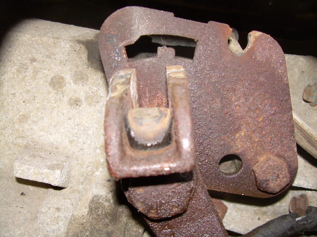 Close-up of a rusted metal bracket, likely part of a transfer case linkage