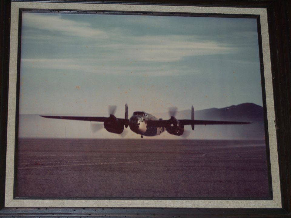 Framed vintage photograph of a twin-engine propeller bomber over desert flats