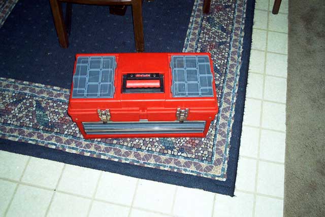 Red Craftsman plastic toolbox sitting on a patterned rug indoors