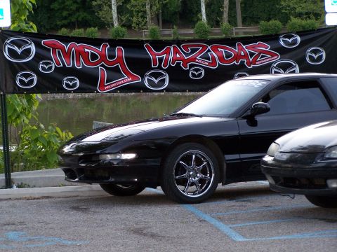 1995 Ford Probe - A black 1995 Ford Probe is parked at an event with a "My Mazdas" banner behind it.