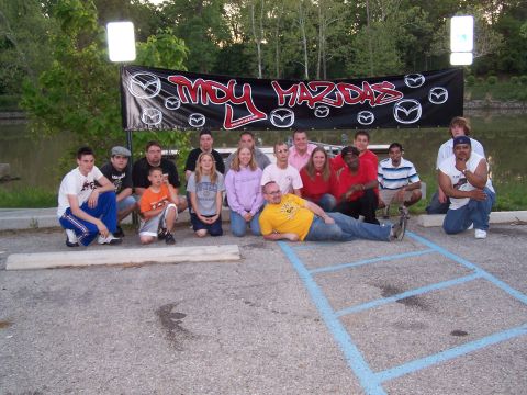 1995 Ford Probe - A group of people gathered for a photo in front of a banner that reads 'Indy Mazdas'.
