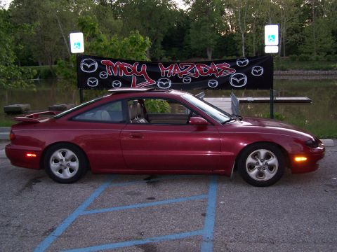 1995 Ford Probe - Red Mazda MX-6 coupe parked under a banner that says 'My Mazdas'.