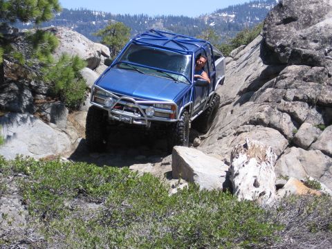 1994 Ford Bronco - Off-road vehicle tackling a challenging rocky mountain path on a sunny day.