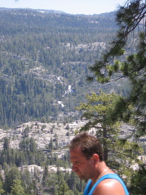 1994 Ford Bronco - Man in blue tank top overlooks a wide, forested mountain vista with a waterfall in the distance.
