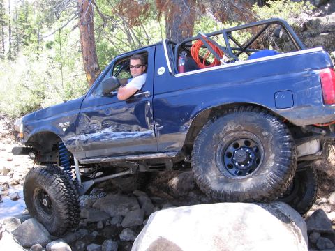 1994 Ford Bronco - Driver navigates a blue 1994 Ford Bronco over a rocky off-road course.