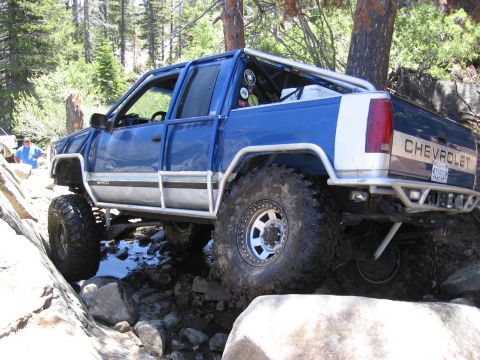 1994 Ford Bronco - Modified Chevrolet pickup truck navigating a rocky stream bed during an off-road excursion.