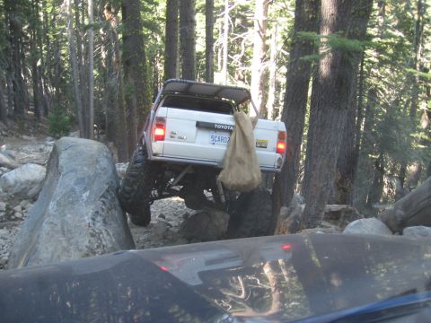 1994 Ford Bronco - Toyota SUV on a challenging off-road trail with large rocks and trees.