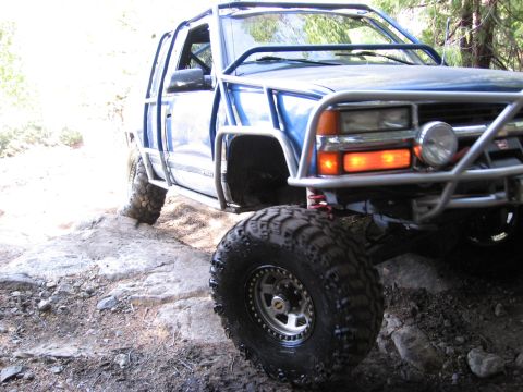 1994 Ford Bronco - A heavily modified blue truck navigates a challenging rocky path.