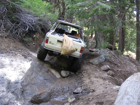 1994 Ford Bronco - Ford Bronco tackling a steep, muddy, and rocky trail in a wooded area.