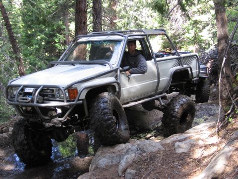1994 Ford Bronco - A modified Toyota pickup truck navigates a challenging off-road trail with another vehicle following behind.