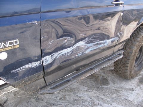 1994 Ford Bronco - The side panel of a 1994 Ford Bronco shows significant damage from off-road use.