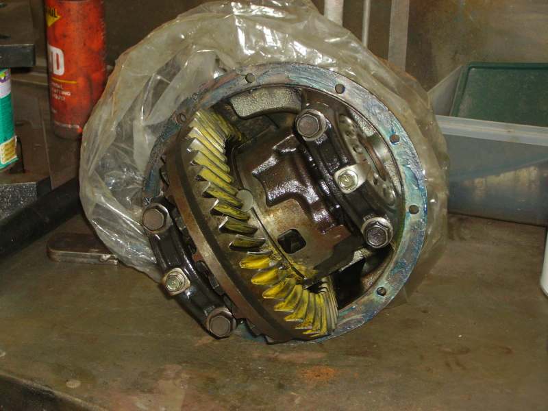 Differential assembly with yellow-marked ring gear sitting on a plastic bag on a workbench