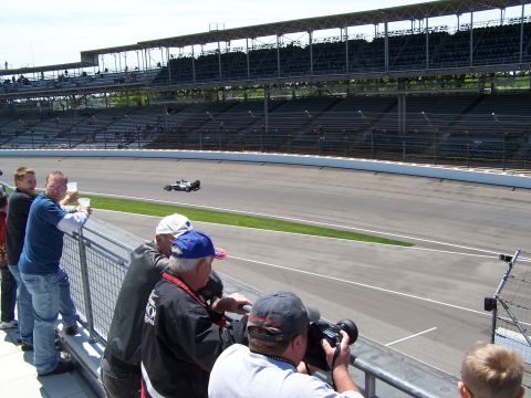 1995 Ford Probe - Spectators watch a race car on a track with grandstands in the background.