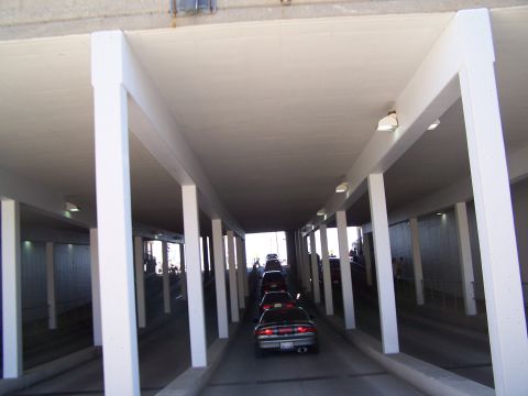 1995 Ford Probe - A line of cars drives through a covered walkway with white pillars on either side.