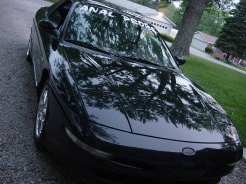 1995 Ford Probe - A black 1995 Ford Probe is shown from a 3/4 front angle, parked on a gravel surface with a banner across the windshield.