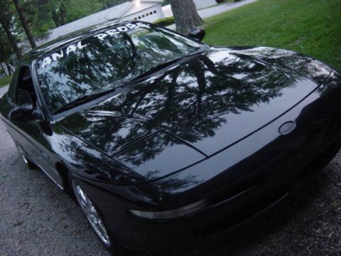 1995 Ford Probe - Black coupe with a banner on the windshield reads "ANAL PROBE".