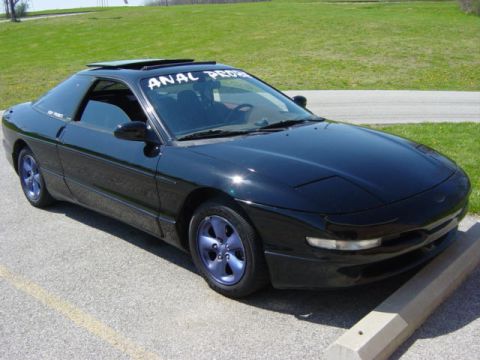 1995 Ford Probe - A black coupe with custom blue wheels is parked outdoors on a sunny day.