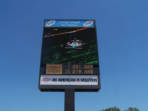 1995 Ford Probe - A large digital billboard displays current speeds and race information under a blue sky.