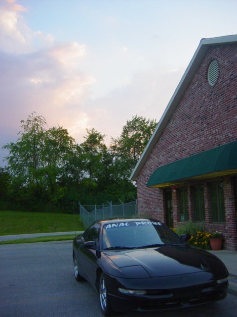 1995 Ford Probe - A black car is parked outside a brick building with a green awning.