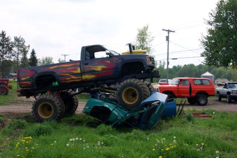 1978 Ford Bronco - A monster truck is shown crushing a car, with other vehicles visible in the background.