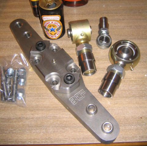 1982 Ford Bronco - Metal steering linkage with BEF logo, hardware, and a Newcastle Brown Ale can are laid out on a wooden surface.