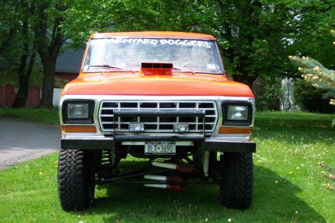 1978 Ford Bronco - This lifted pickup truck has a prominent hood scoop and a custom decal on the windshield.
