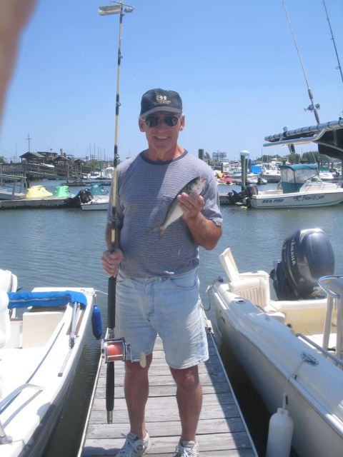 1979 Ford F-250 - A man proudly displays his catch while standing on a dock surrounded by boats.