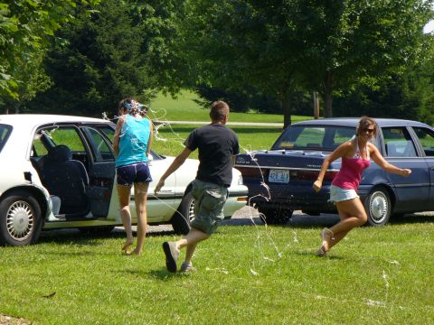 1991 Ford Probe - People are running around two cars in a grassy area, with streamers flying through the air.