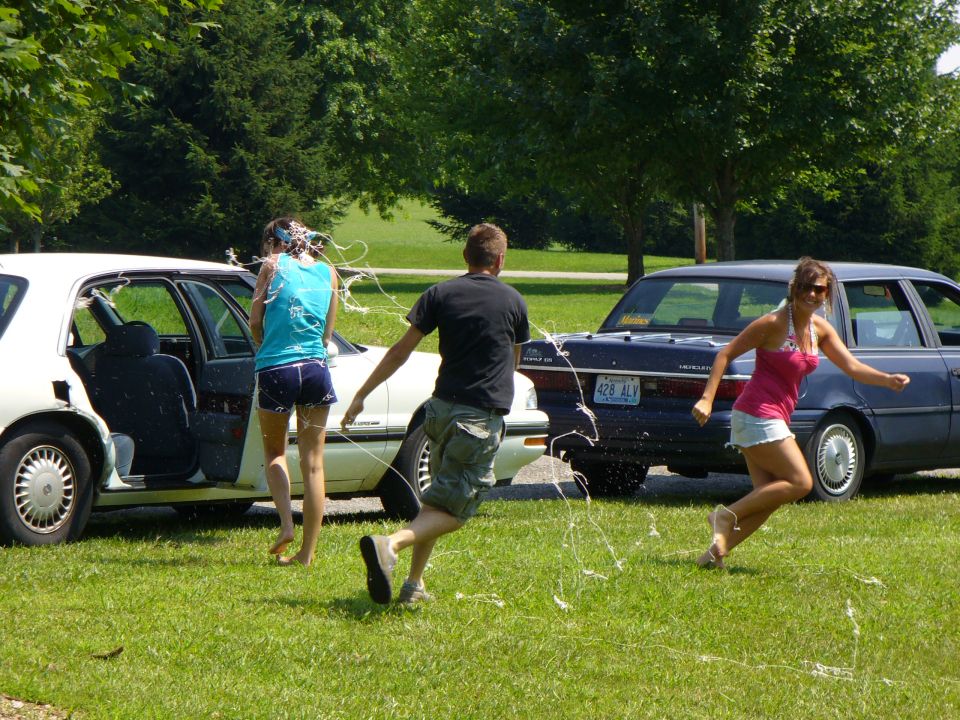 Two cars with people running and streamers flying