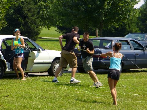 1991 Ford Probe - Two cars are parked in a grassy area while people engage in a water gun activity.