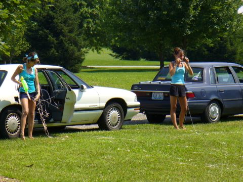 1991 Ford Probe - Two women stand by sedans parked on a grassy area with trees in the background.