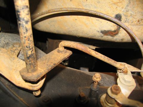 1978 Ford Bronco - Close-up view of rusted linkage and brake line components beneath a vehicle.