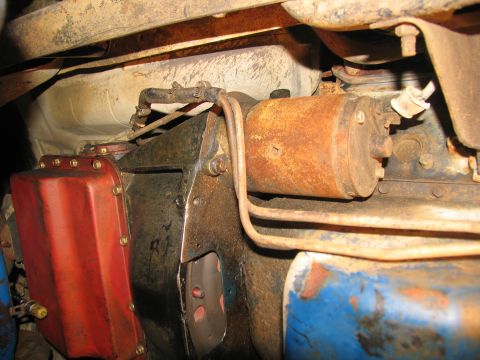 1978 Ford Bronco - Underside view of a vehicle's rusty starter motor and transmission pan.